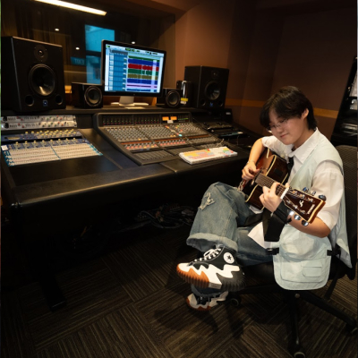 Student playing guitar in a recording studio